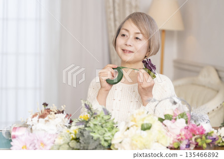 一位老婦人在客廳以插花為樂 135466892