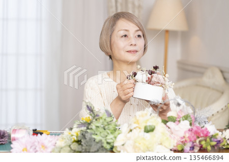 Senior woman arranging flowers as a hobby in the living room Senior woman arranging flowers as a hobby in the living room 135466894