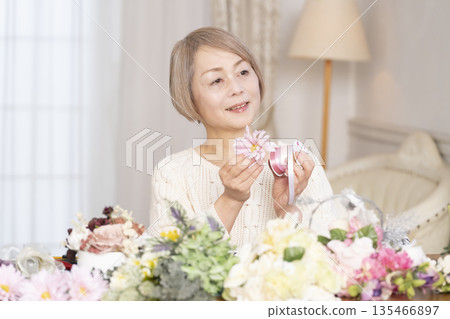 一位老婦人在客廳以插花為樂 一位老婦人在客廳以插花為樂 135466897