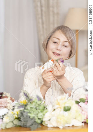 Senior woman arranging flowers as a hobby in the living room 135466902