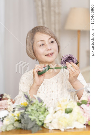 Senior woman arranging flowers as a hobby in the living room 135466906