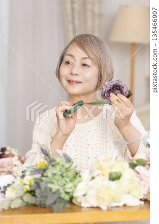 Senior woman arranging flowers as a hobby in the living room 135466907