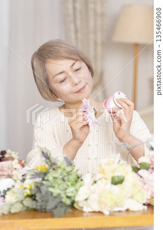 Senior woman arranging flowers as a hobby in the living room 135466908