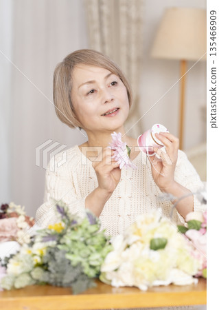 Senior woman arranging flowers as a hobby in the living room 135466909