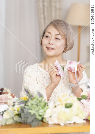 一位老婦人在客廳以插花為樂 一位老婦人在客廳以插花為樂 135466913