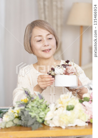 Senior woman arranging flowers as a hobby in the living room 135466914