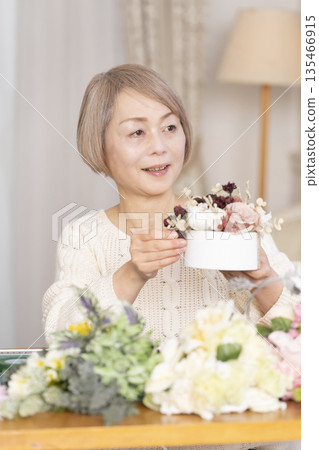 Senior woman arranging flowers as a hobby in the living room 135466915