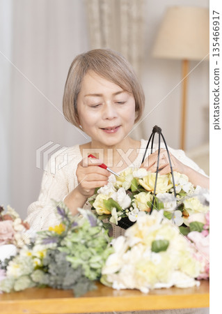 一位老婦人在客廳以插花為樂 一位老婦人在客廳以插花為樂 135466917