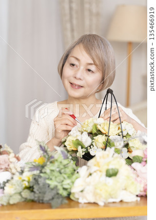 一位老婦人在客廳以插花為樂 一位老婦人在客廳以插花為樂 135466919
