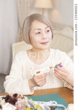 一位老婦人在客廳以插花為樂 一位老婦人在客廳以插花為樂 135466921