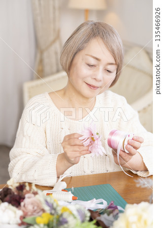 Senior woman arranging flowers as a hobby in the living room 135466926