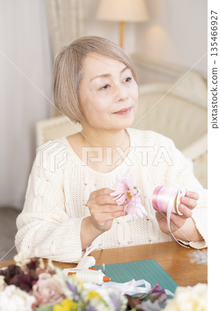 Senior woman arranging flowers as a hobby in the living room 135466927