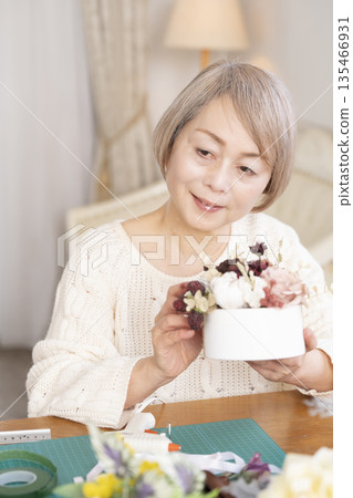 Senior woman arranging flowers as a hobby in the living room 135466931