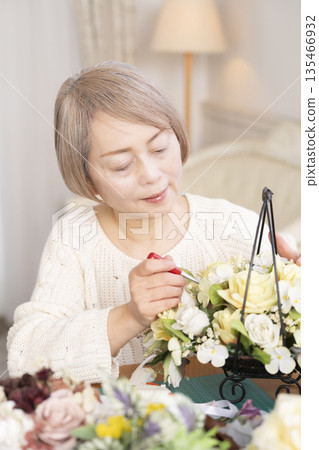 一位老婦人在客廳以插花為樂 一位老婦人在客廳以插花為樂 135466932