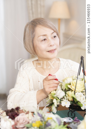 一位老婦人在客廳以插花為樂 一位老婦人在客廳以插花為樂 135466933