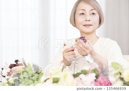 一位老婦人在客廳以插花為樂 一位老婦人在客廳以插花為樂 135466939