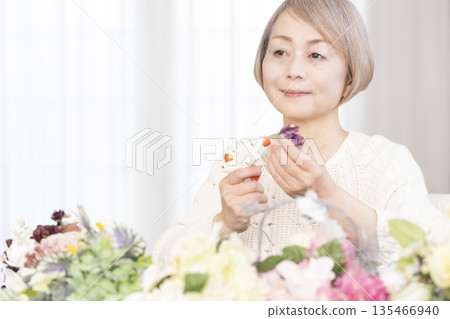 Senior woman arranging flowers as a hobby in the living room 135466940