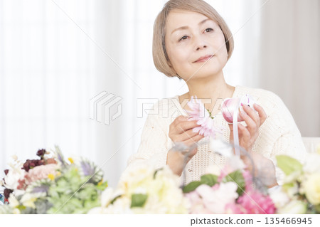 Senior woman arranging flowers as a hobby in the living room 135466945