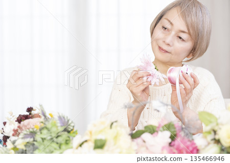 一位老婦人在客廳以插花為樂 一位老婦人在客廳以插花為樂 135466946