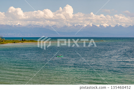Two people rowing in a small boat on tranquil Issyk-Kul lake 135468452