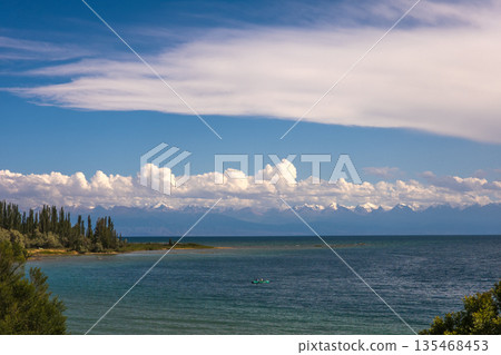 Two people boating on green boat in serene Issyk-Kul lake landscape 135468453