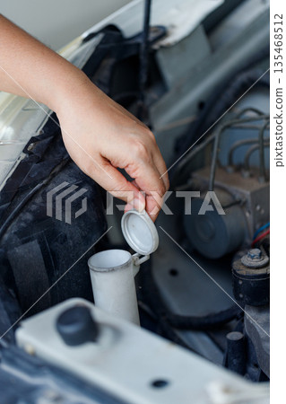 Close up of a hand of woman is checking a liquid coolant pot 135468512