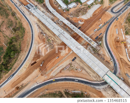 The construction site before the construction of the concrete bridge over the intersection by crane workers, tractors, and backhoes 135468515