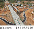 The construction site before the construction of the concrete bridge over the intersection by crane workers, tractors, and backhoes 135468516