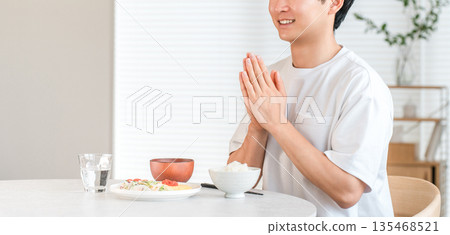 年輕的亞洲男子在家裡的餐桌上吃飯(Itadakimasu) 年輕的亞洲男子在家裡的餐桌上吃飯(Itadakimasu) 135468521