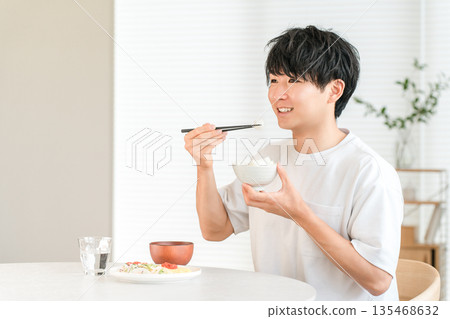 餐桌上的米飯,一位年輕的亞洲男子正在吃白米飯。 餐桌上的米飯,一位年輕的亞洲男子正在吃白米飯。 135468632