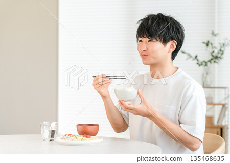 餐桌上的米飯，一位年輕的亞洲男子正在吃白米飯。 135468635