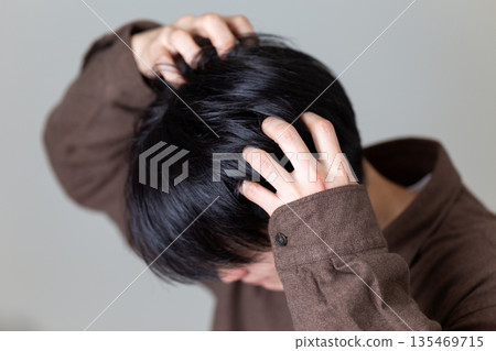 A middle-aged man suffering from itchy scalp A middle-aged man suffering from itchy scalp 135469715
