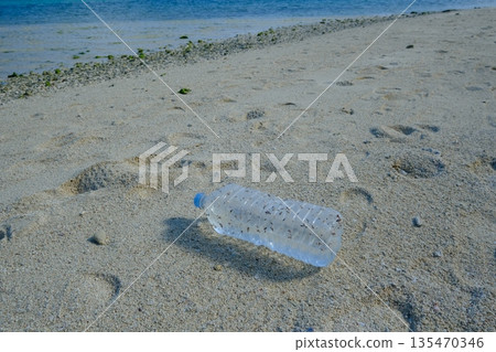 一個裝有貝殼的塑膠瓶被沖上了海灘。 一個裝有貝殼的塑膠瓶被沖上了海灘。 135470346