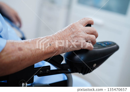 Asian elderly disability woman patient use joystick electric wheelchair in hospital. 135470657