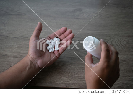 Close up hands pouring pills into palm from medicine bottle, medication dosage concept, healthcare treatment, daily routine and responsible drug use. 135471004
