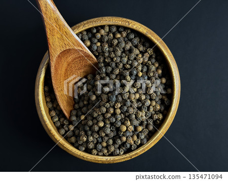 Black Peppercorns in a Wooden Bowl with Spoon on Dark Background 135471094