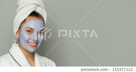 Smiling healthy woman in blue clay cosmetic face mask indoor portrait. Facial treatment Smiling healthy woman in blue clay cosmetic face mask indoor portrait. Facial treatment 135471122