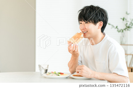 年輕的亞洲男子早餐吃烤麵包和沙拉。 135472116