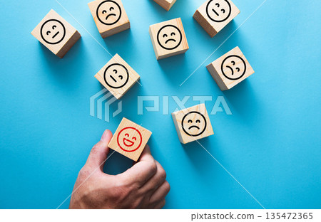 Hand picking happy smiley block for customer feedback concept 135472365