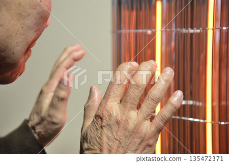 一位老人正在用電暖器取暖。 135472371