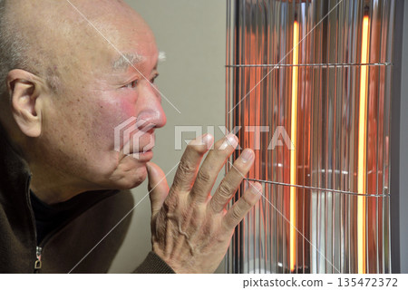 一位老人正在用電暖器取暖。 135472372