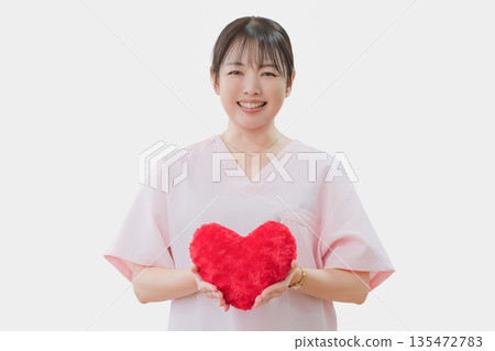 Smiling medical woman holding a heart 135472783