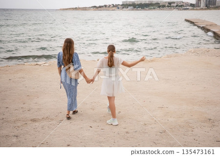 Beach Girls Walking Croatia Summer: Two girls stroll hand-in-hand along a Croatian beach during summer, enjoying a coastal vacation. Beach Girls Walking Croatia Summer: Two girls stroll hand-in-hand along a Croatian beach during summer, enjoying a coastal vacation. 135473161