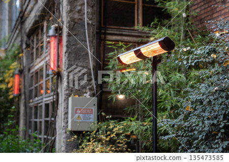 Street cafe with open-air terrace using infrared heater for comfortable time spending outdoors. Street cafe with open-air terrace using infrared heater for comfortable time spending outdoors. 135473585