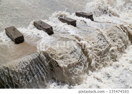 Concrete blocks in flowing water, turbulent river scene Concrete blocks in flowing water, turbulent river scene 135474583