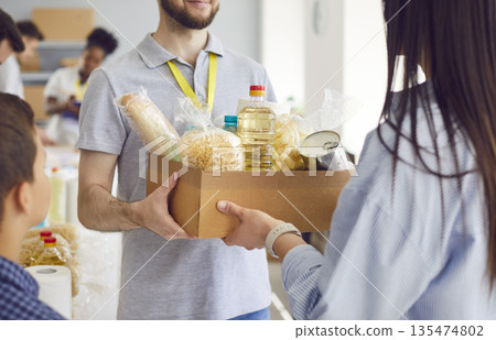 Close Up Of Volunteer Hands Passing Food Box To Refugee Close Up Of Volunteer Hands Passing Food Box To Refugee 135474802