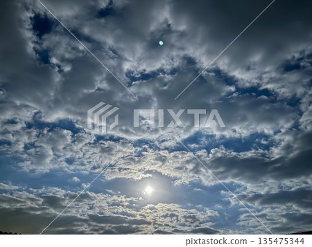 A bright full moon in a cloudy night sky. This phenomenon highlights the reflected sunlight from the moon against the dark sky, while the cloud cover softens it. A bright full moon in a cloudy night sky. This phenomenon highlights the reflected sunlight from the moon against the dark sky, while the cloud cover softens it. 135475344