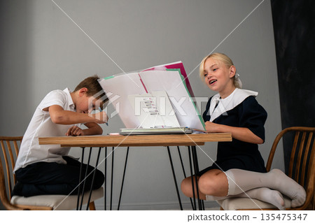 Kids Laptop Learning Online Education - Two children, a boy and a girl, are sitting at a table with a laptop and books. 135475347