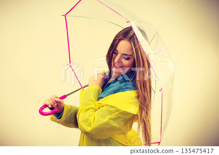 Woman wearing waterproof coat under umbrella 135475417