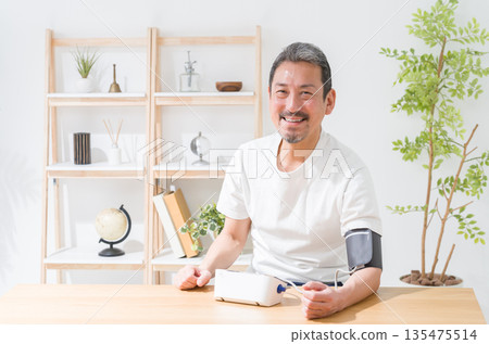 一位中年男子正在用血壓計測量血壓 135475514